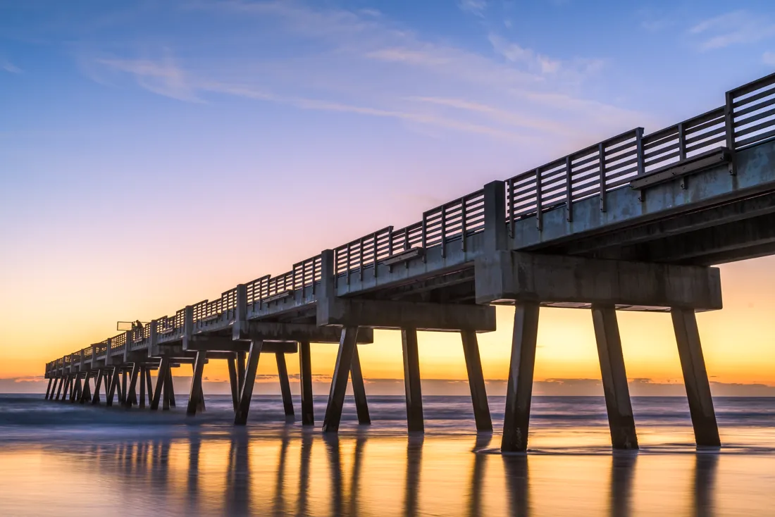 The Jacksonville Beach pier reaching into calm water at dusk