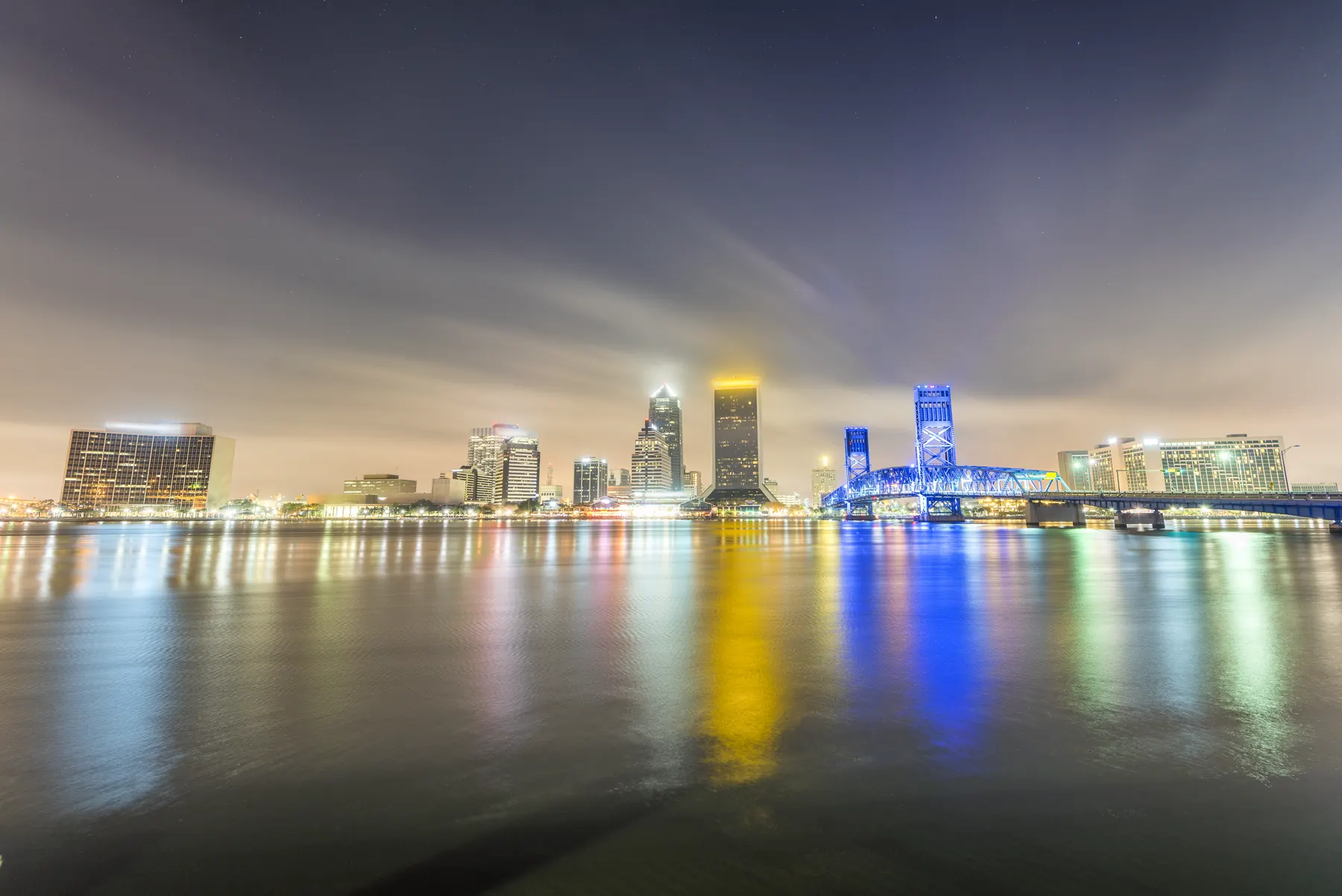 The Jacksonville skyline at night, lights reflecting off the St Johns River