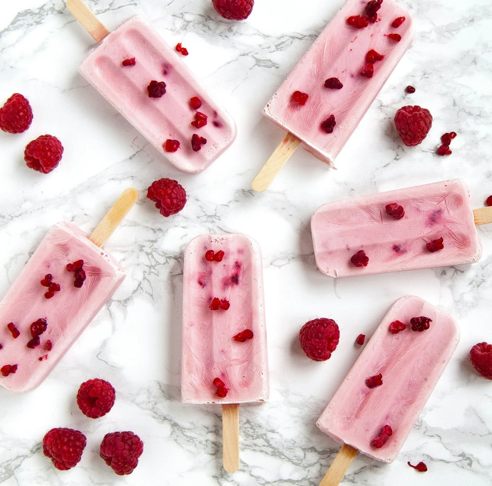 Bright fruit popsicles laid out on a pale surface, food without rules attached