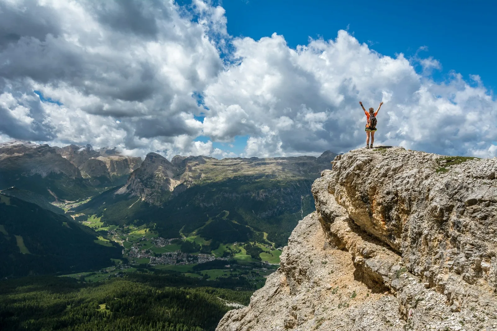 A lone figure standing at a mountain summit looking out across a valley