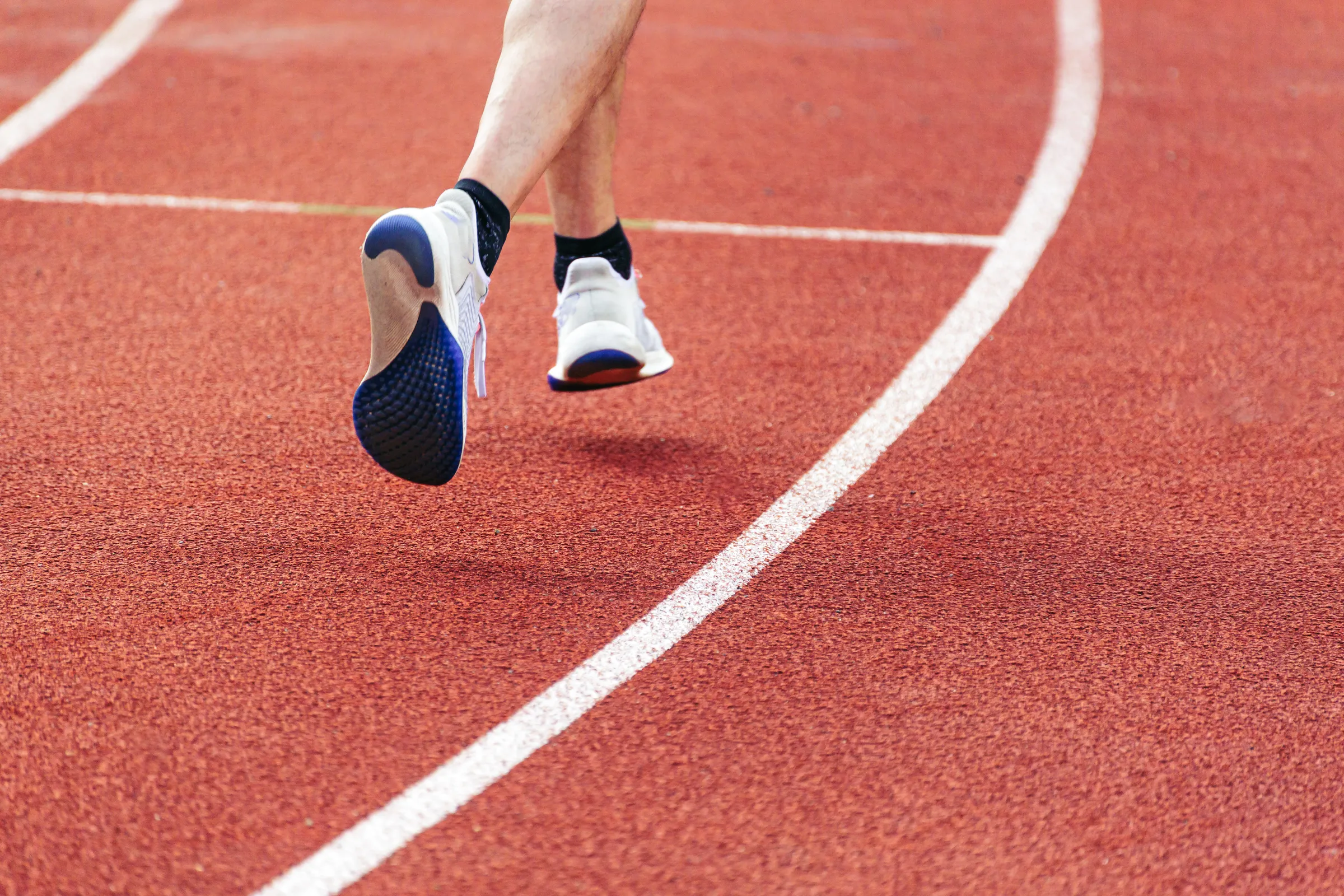 A runner's shoes mid stride on a red track