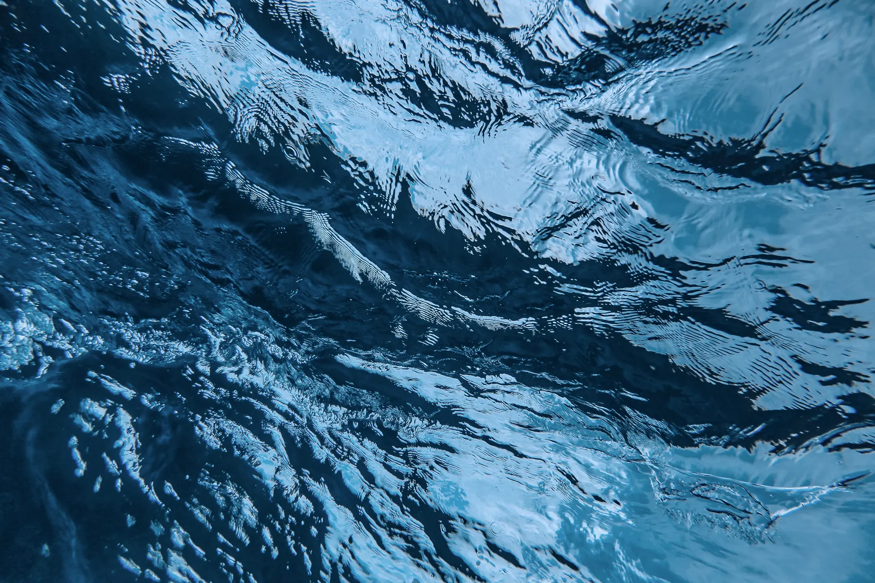 Turquoise water churning into pale ripples, seen from above
